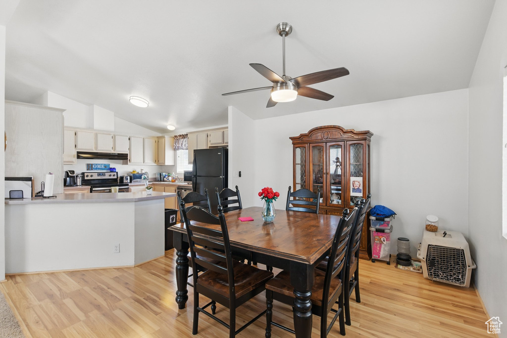 Dining space with light wood-style flooring, ceiling fan, and vaulted ceiling