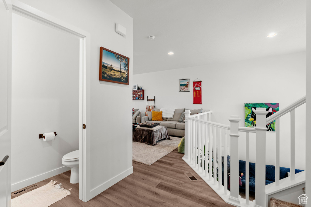 Corridor featuring wood finished floors, recessed lighting, and an upstairs landing