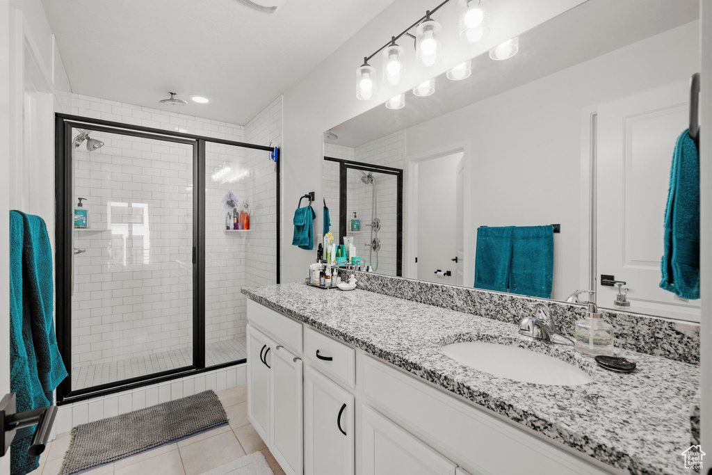 Full bathroom with vanity, a shower stall, and tile patterned floors