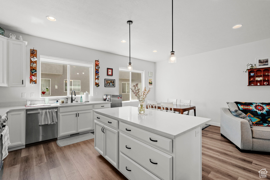Kitchen with stainless steel appliances, light wood finished floors, white cabinetry, light countertops, and recessed lighting
