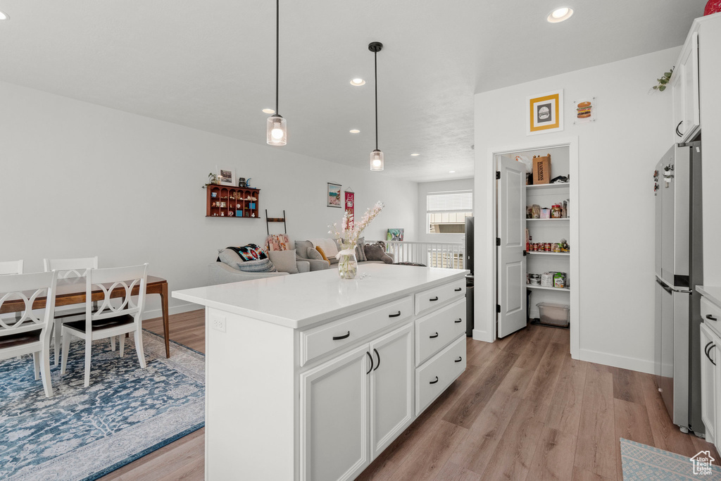 Kitchen with freestanding refrigerator, light wood-style floors, recessed lighting, light countertops, and white cabinetry