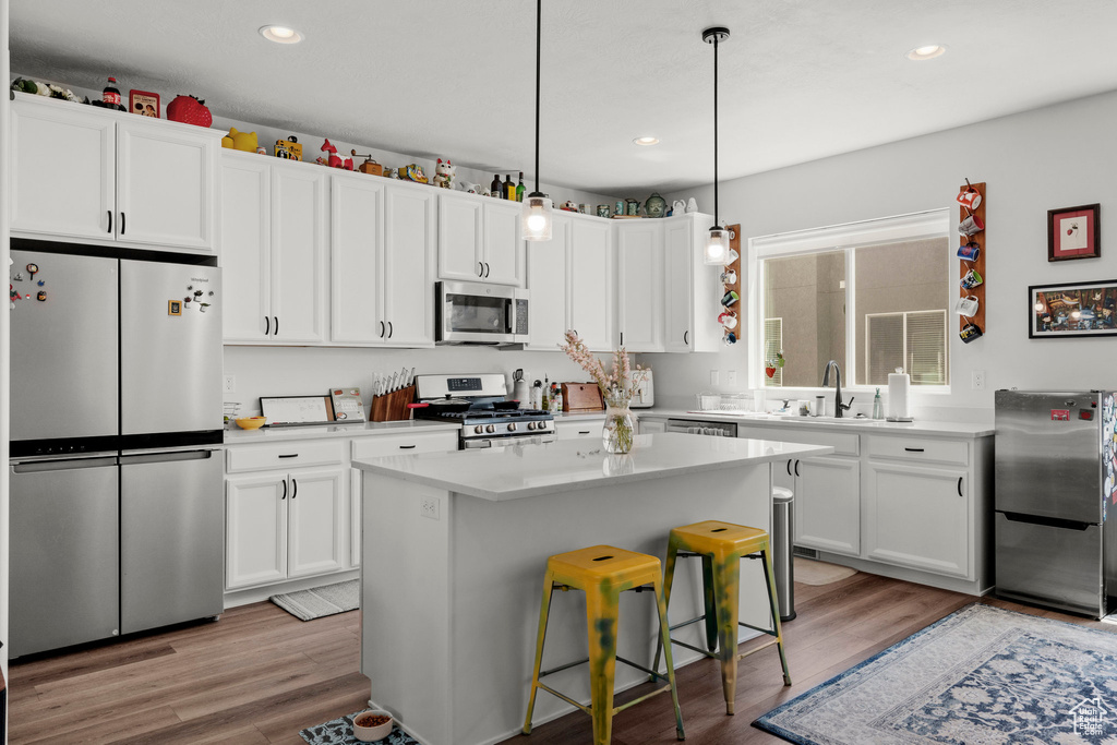 Kitchen with appliances with stainless steel finishes, white cabinetry, light countertops, light wood-style floors, and recessed lighting