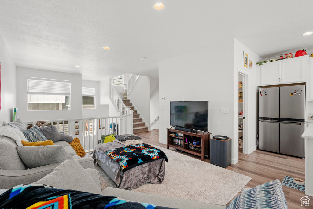 Living area featuring light wood-style flooring, recessed lighting, and stairway