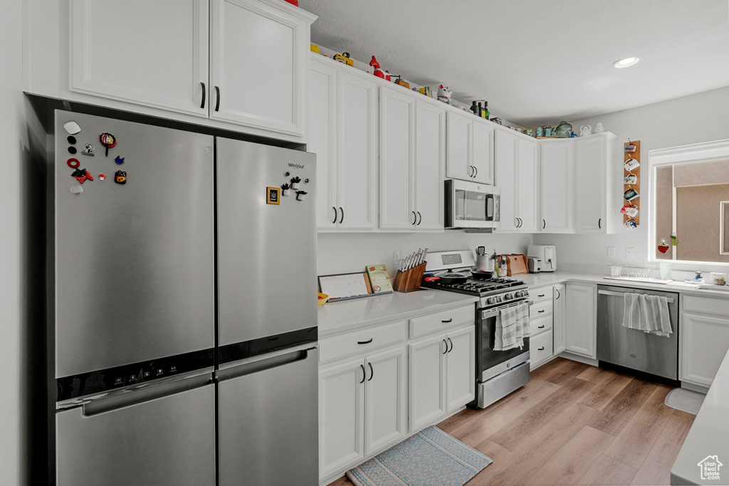 Kitchen featuring stainless steel appliances, light countertops, white cabinets, and recessed lighting