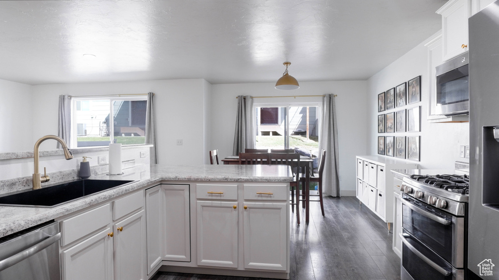 Kitchen with stainless steel appliances, healthy amount of natural light, dark wood-style flooring, and white cabinets
