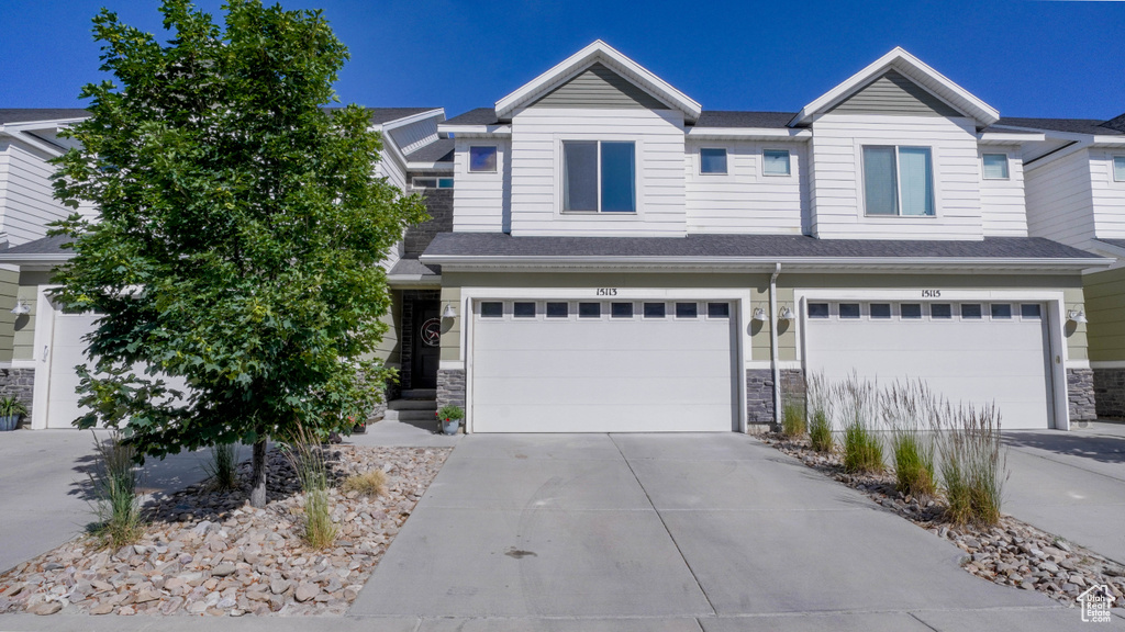 Townhome / multi-family property featuring stone siding, concrete driveway, and a garage