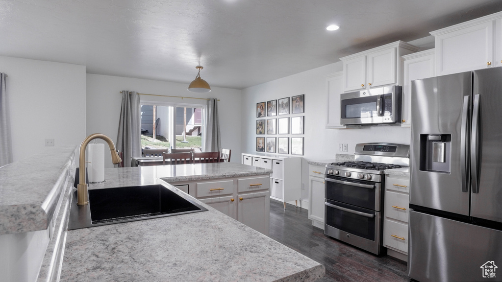 Kitchen with appliances with stainless steel finishes, dark wood-style floors, white cabinetry, recessed lighting, and a peninsula