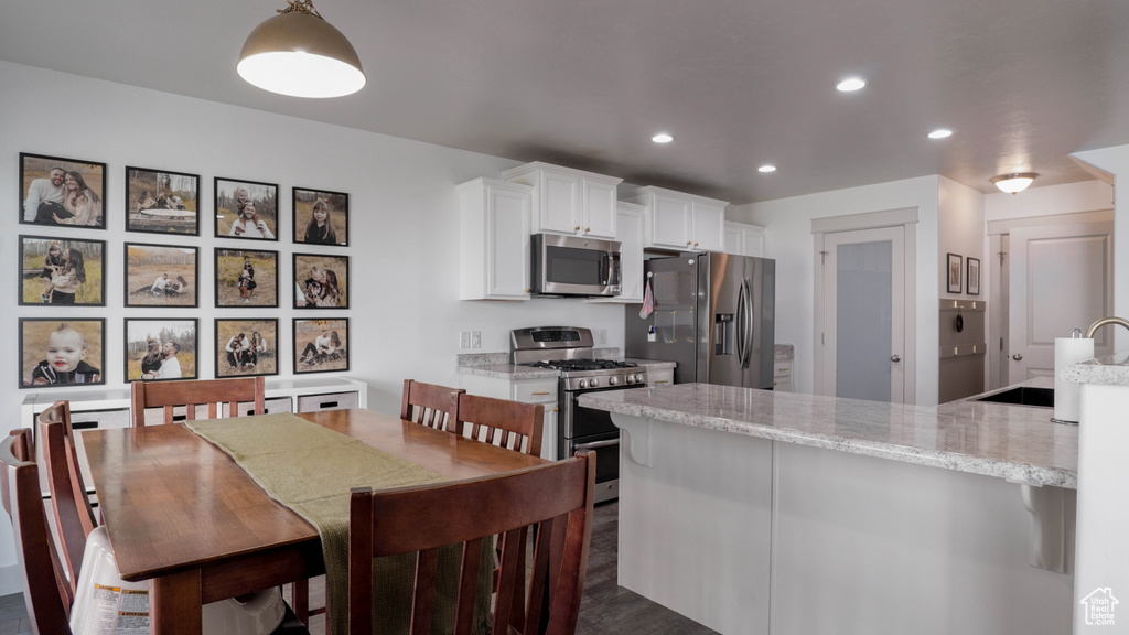 Kitchen featuring appliances with stainless steel finishes, recessed lighting, white cabinets, and light stone counters