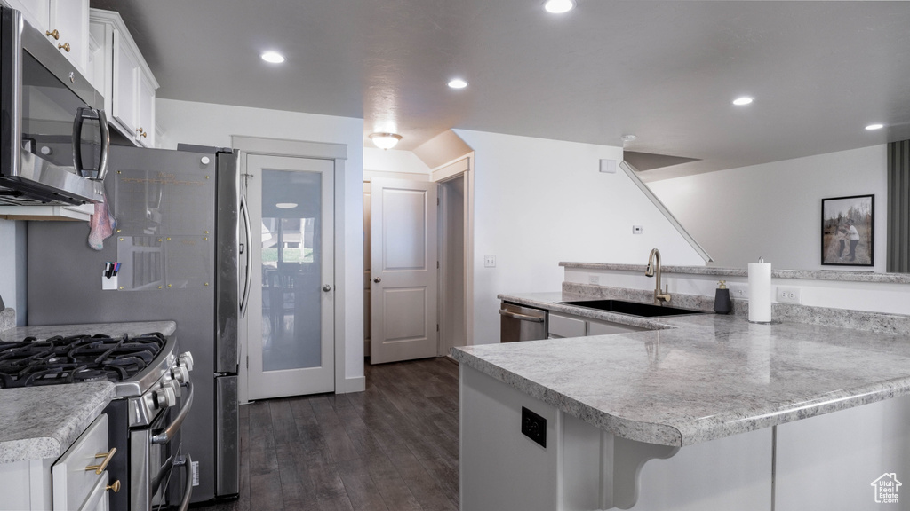Kitchen with appliances with stainless steel finishes, white cabinets, dark wood-type flooring, and recessed lighting