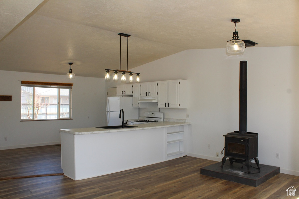 Kitchen featuring white appliances, a peninsula, white cabinets, lofted ceiling, and dark wood-style floors