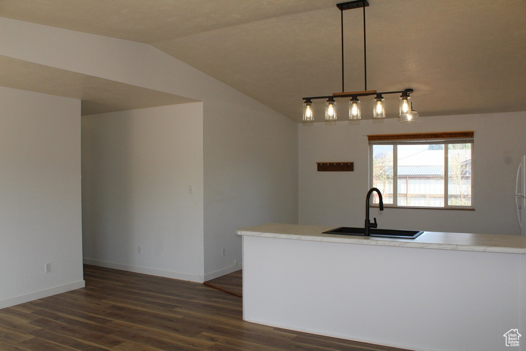 Kitchen featuring dark wood-style flooring, lofted ceiling, light countertops, and pendant lighting