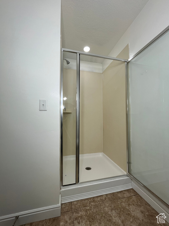 Full bath featuring a stall shower and a textured ceiling