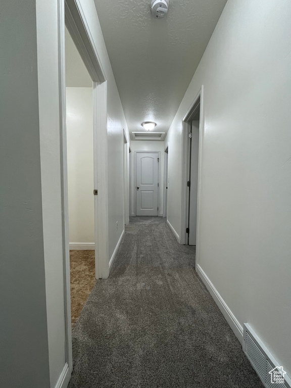 Corridor featuring carpet, attic access, and a textured ceiling