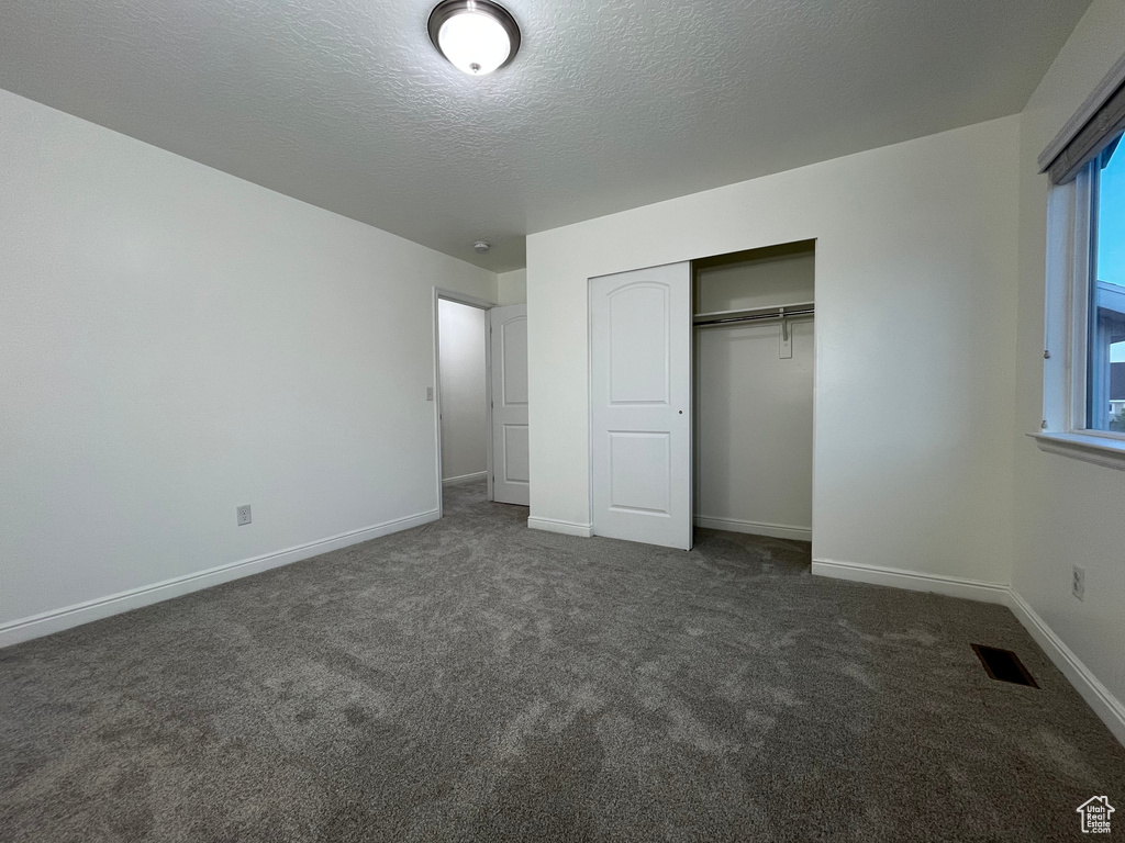 Unfurnished bedroom featuring carpet, a closet, and a textured ceiling