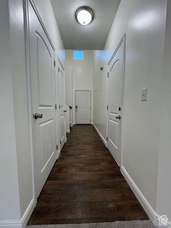 Corridor featuring dark wood finished floors and a textured ceiling