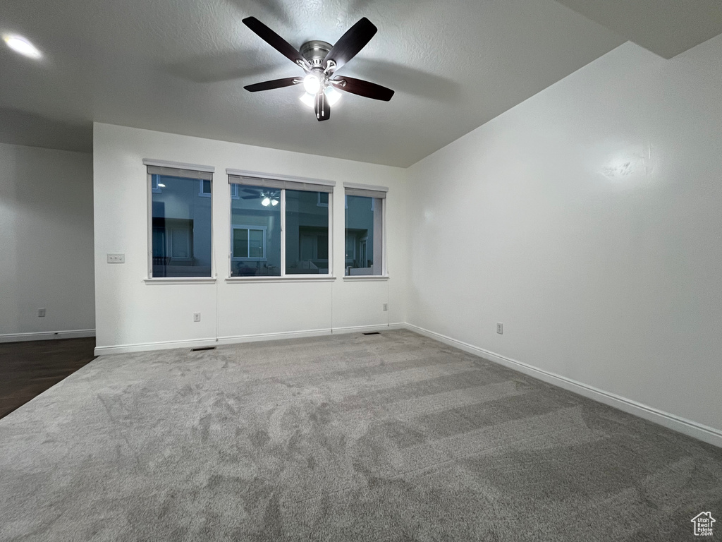 Carpeted spare room featuring ceiling fan and a textured ceiling