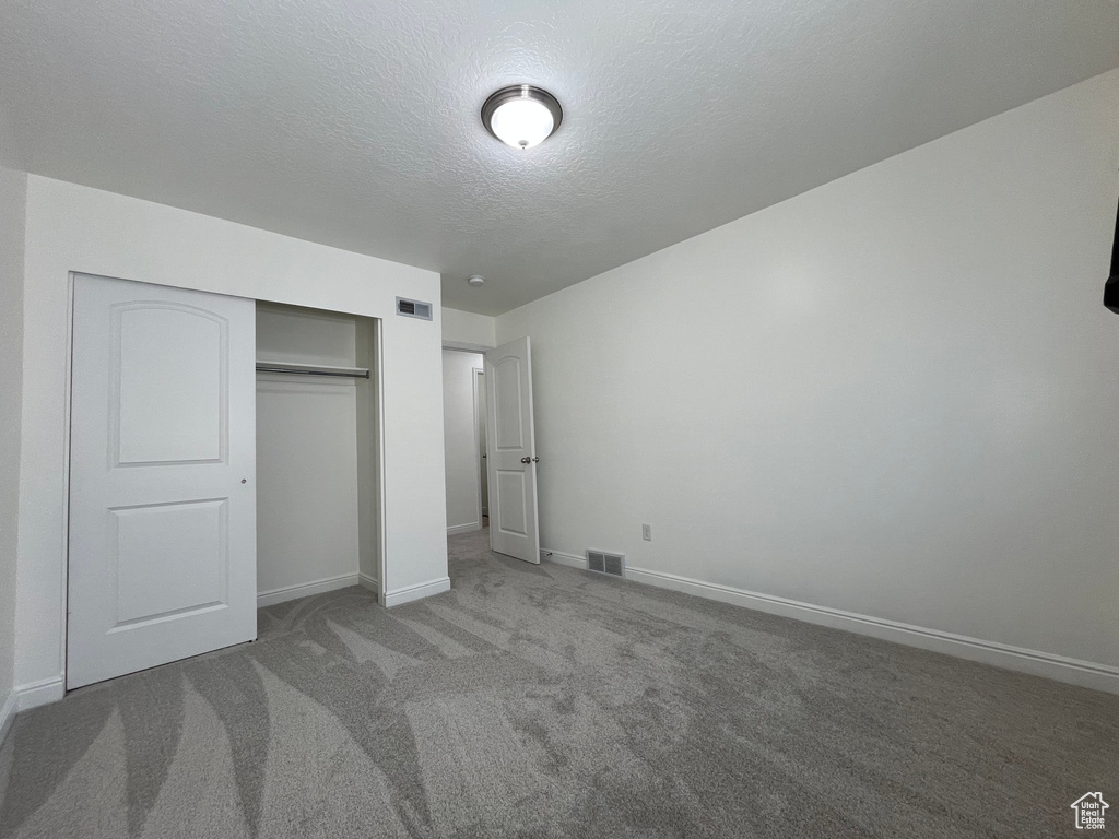Unfurnished bedroom with carpet flooring, a closet, and a textured ceiling