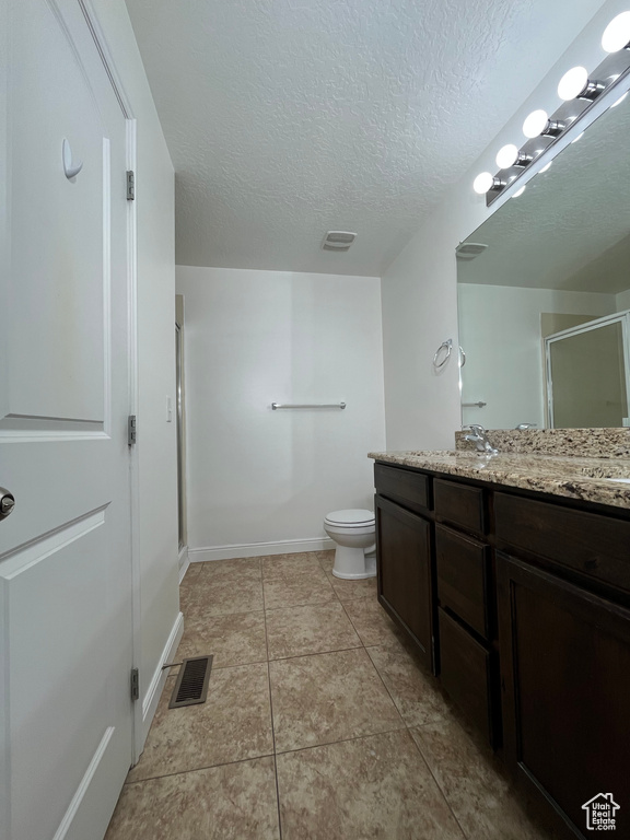 Bathroom featuring double vanity, a shower stall, a textured ceiling, and tile patterned flooring