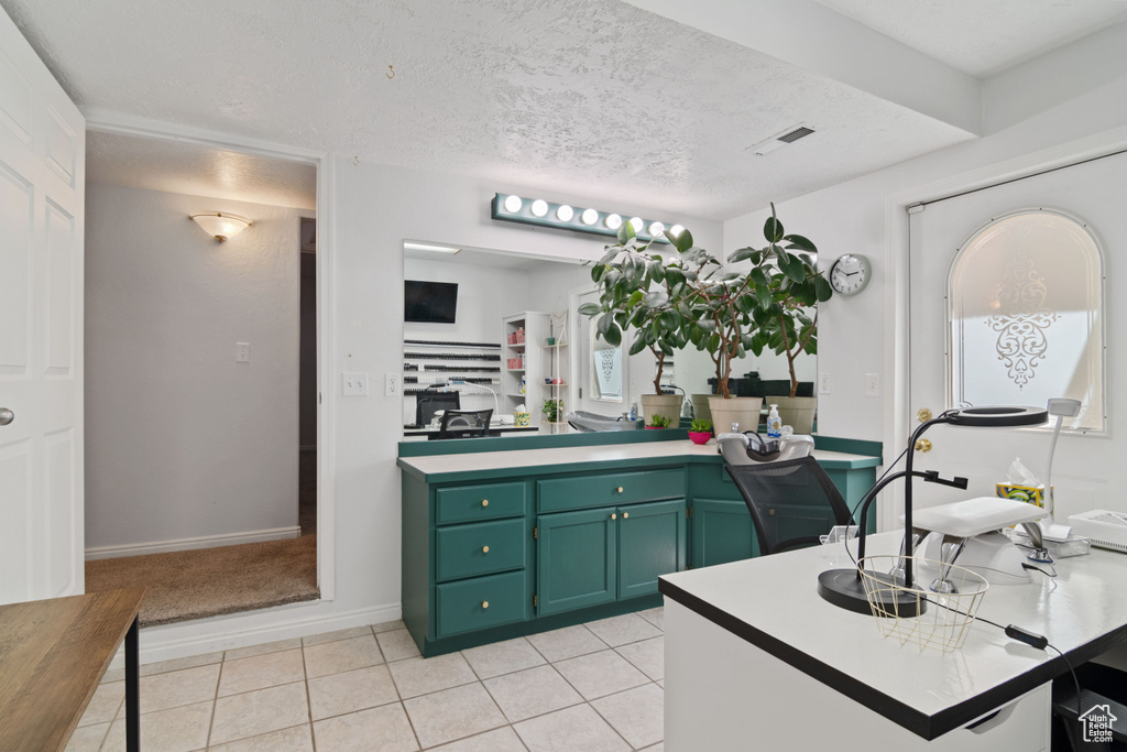 Kitchen featuring green cabinets, light tile patterned floors, and light countertops