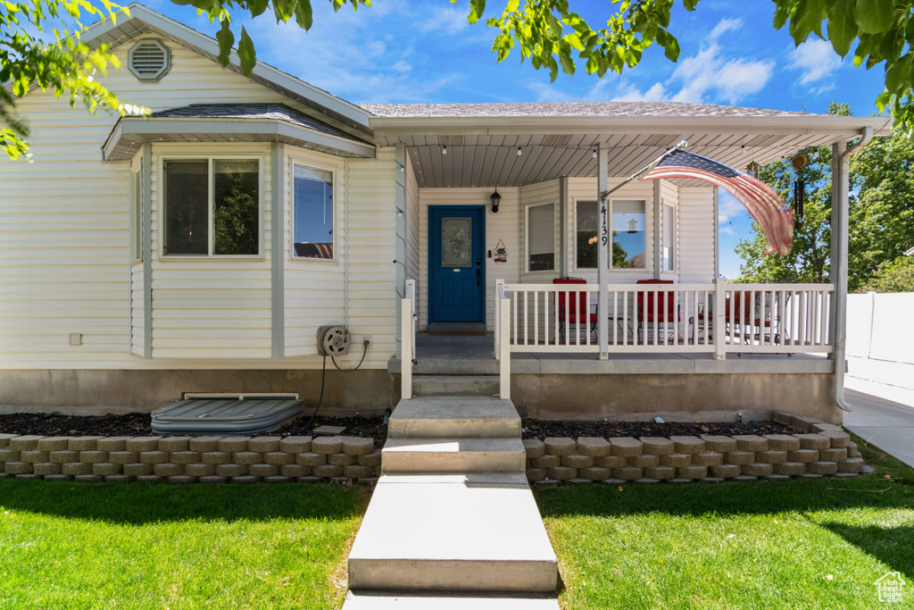 View of front of property featuring covered porch and a front yard