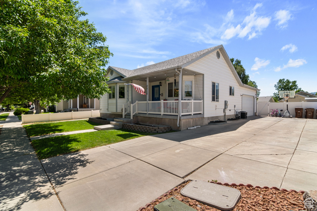 View of front facade featuring a porch, concrete driveway, a garage, and a shingled roof