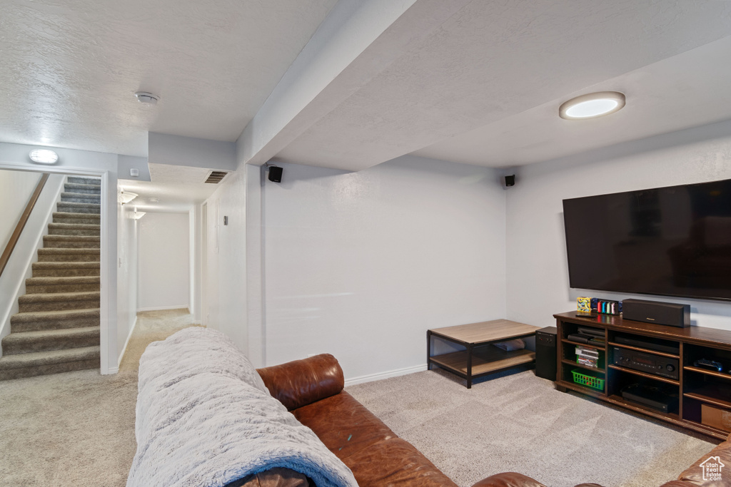 Carpeted living area with stairs and baseboards
