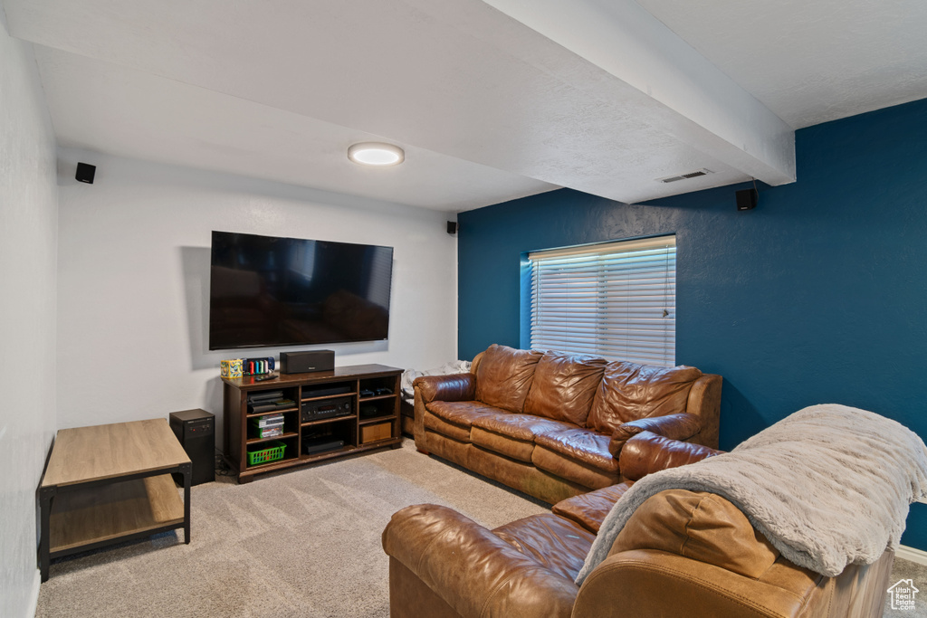Carpeted living room featuring beamed ceiling