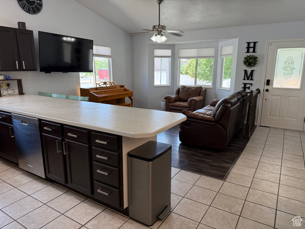 Kitchen with stainless steel dishwasher, light tile patterned flooring, light countertops, a peninsula, and vaulted ceiling
