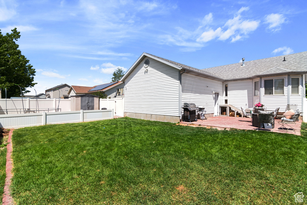 Rear view of property featuring a patio area, a storage shed, and a shingled roof