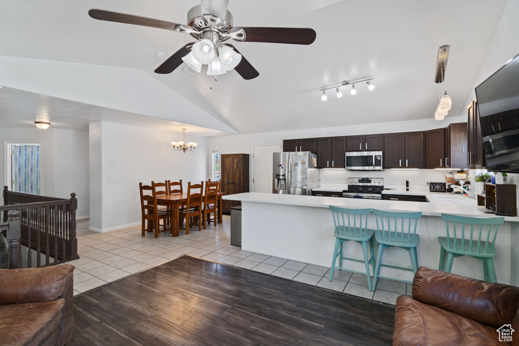 Kitchen featuring stainless steel appliances, open floor plan, light countertops, a chandelier, and vaulted ceiling