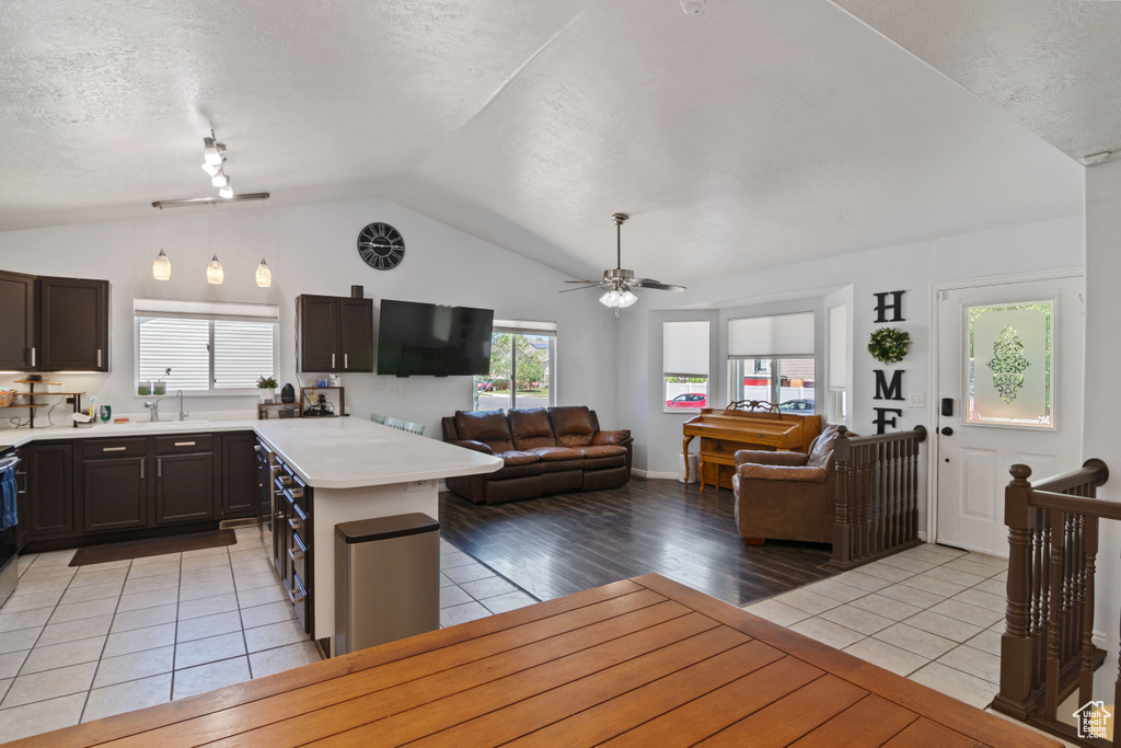 Kitchen featuring ceiling fan, light countertops, lofted ceiling, open floor plan, and light tile patterned floors