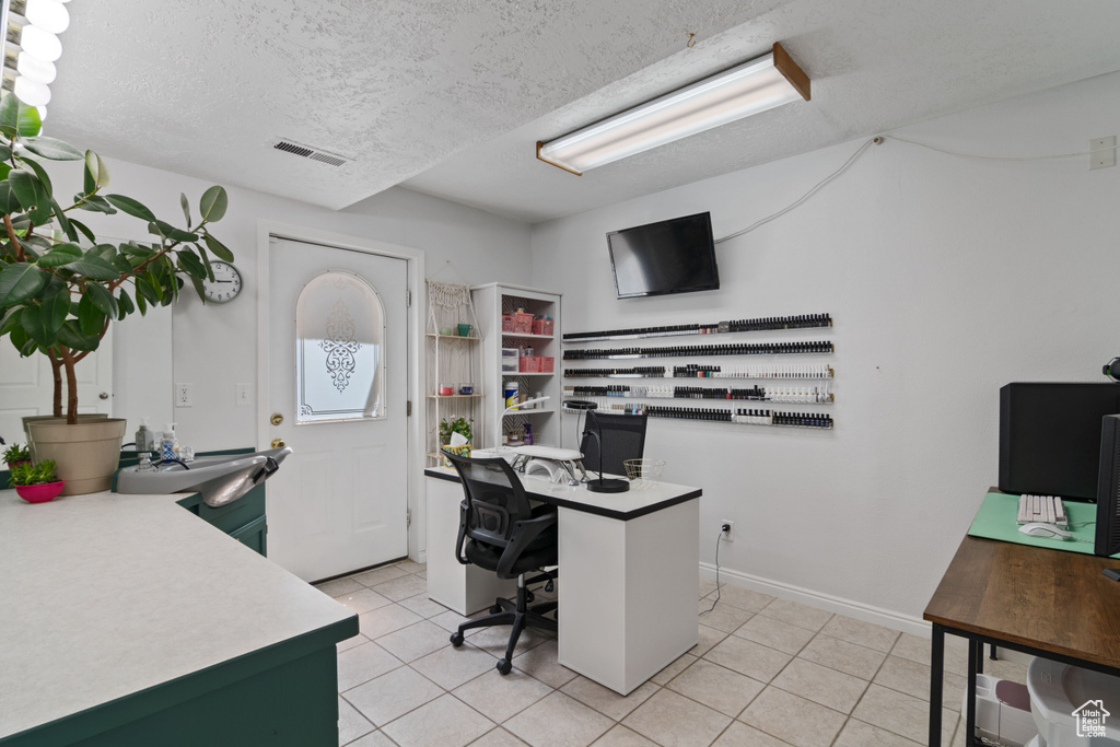 Home office with light tile patterned floors and a textured ceiling