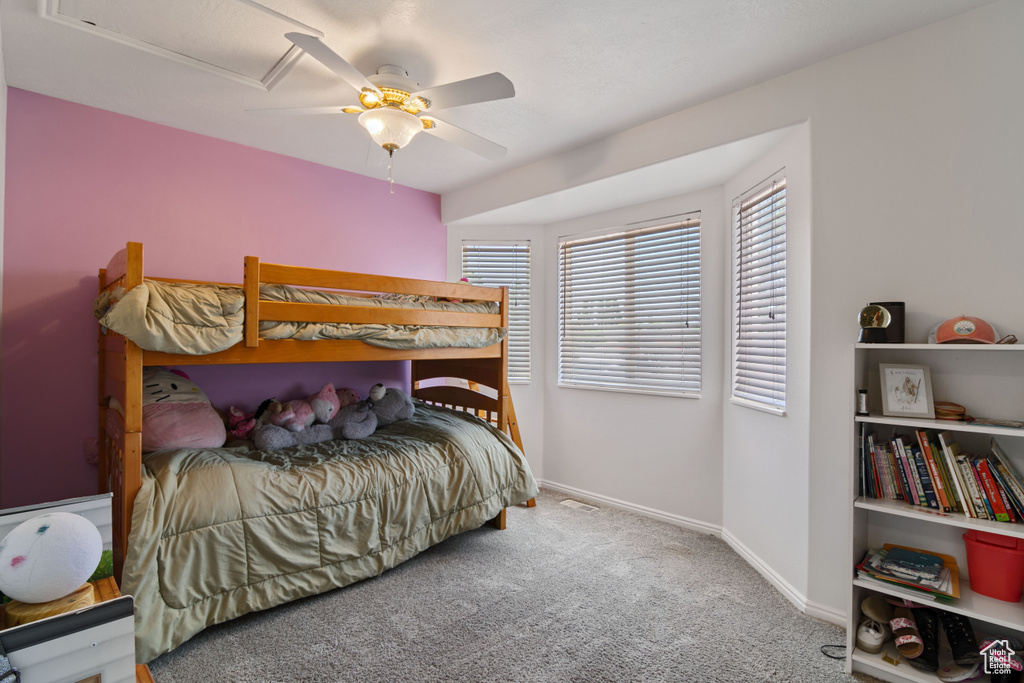 Bedroom with carpet floors, a ceiling fan, and attic access