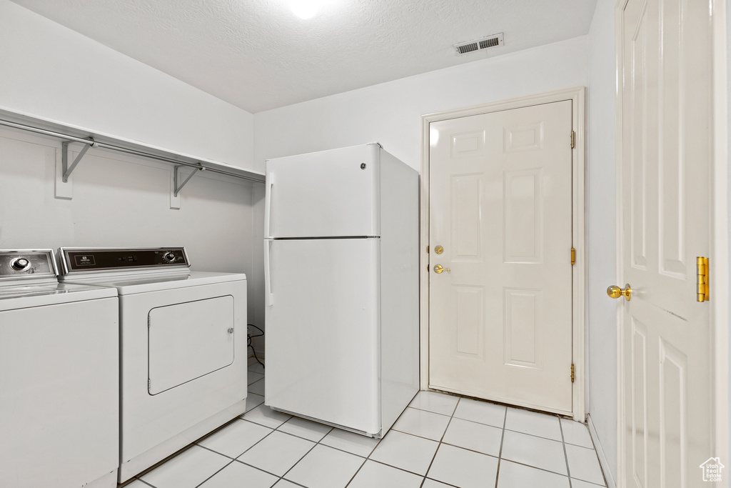 Washroom featuring washing machine and dryer and light tile patterned floors