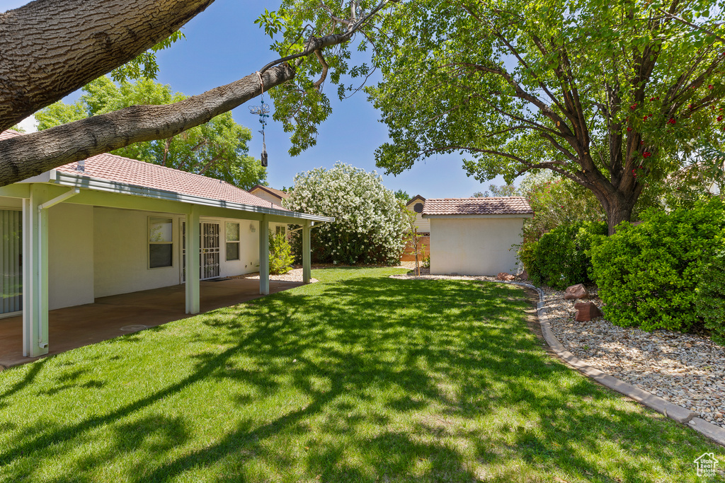 View of grassy yard featuring a patio and an outdoor structure