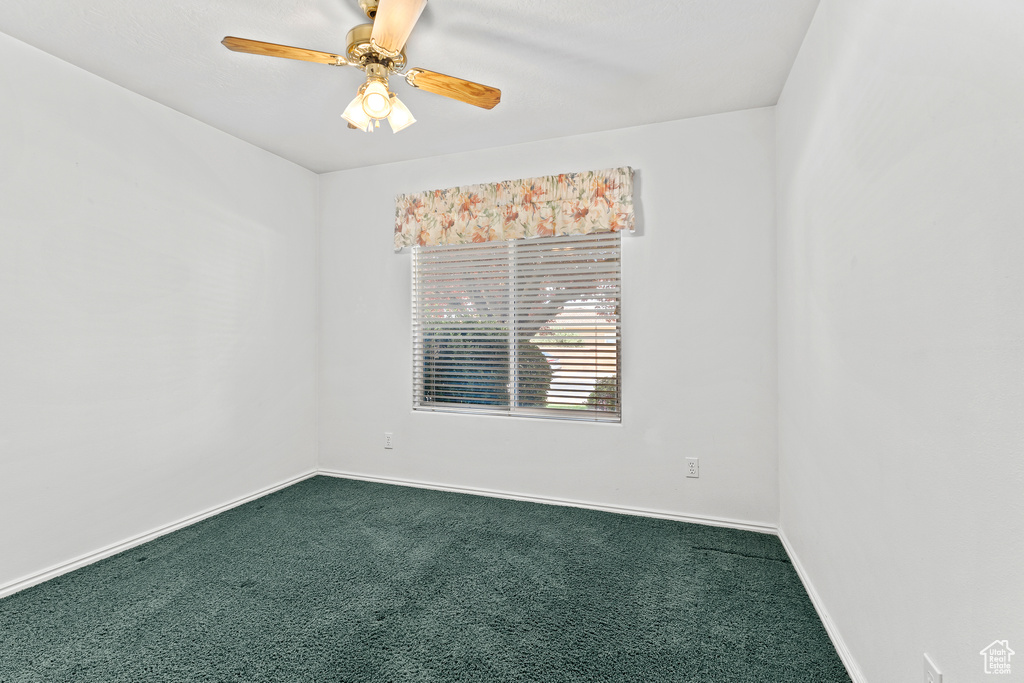 Unfurnished room with dark colored carpet, baseboards, and ceiling fan
