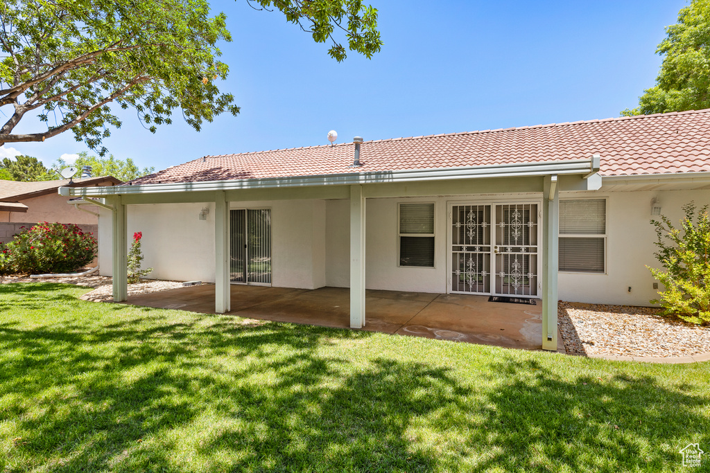 Back of house featuring stucco siding, a tile roof, a patio area, and a yard