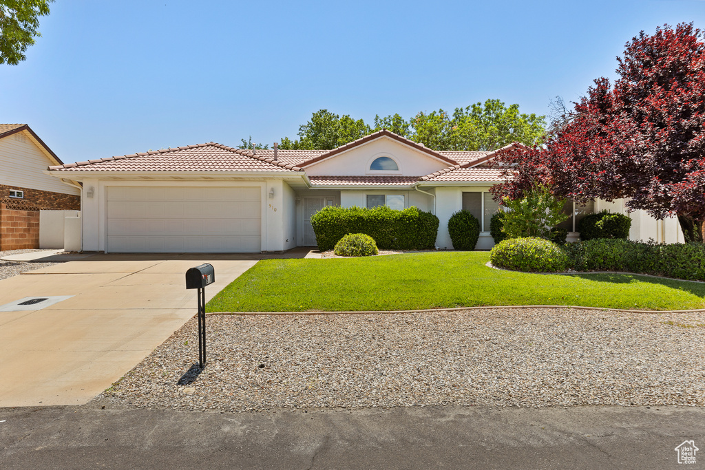 Mediterranean / spanish house with an attached garage, a tiled roof, concrete driveway, and stucco siding