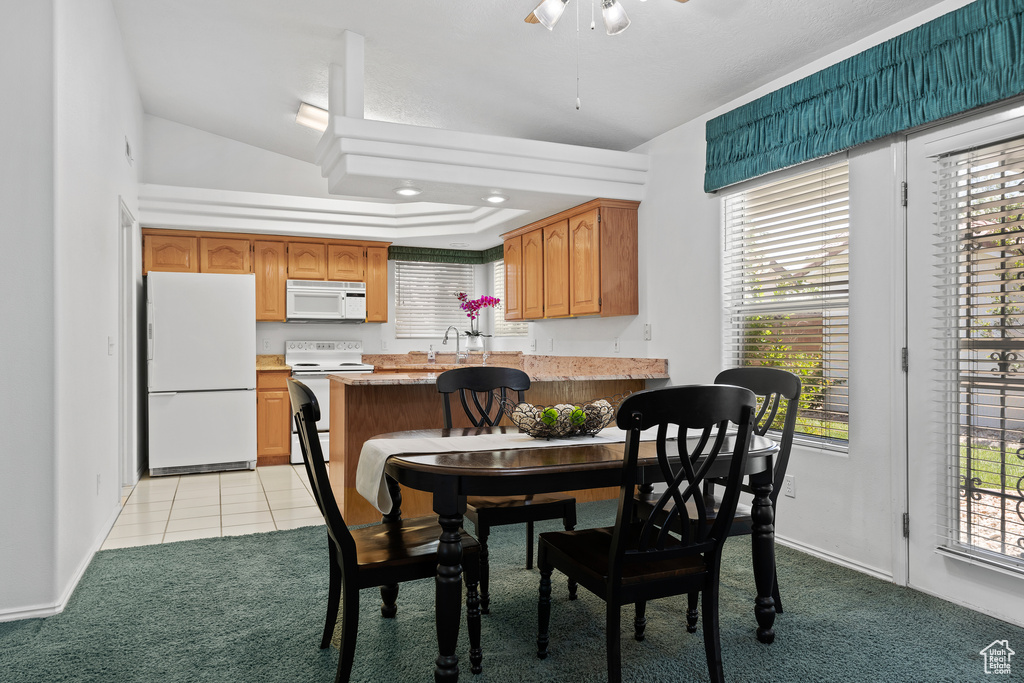 Dining room featuring light colored carpet, a ceiling fan, light tile patterned floors, and baseboards