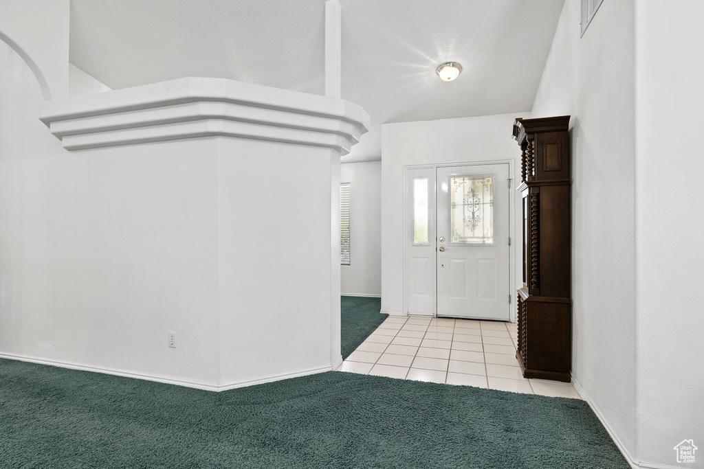 Carpeted entryway featuring tile patterned floors and baseboards