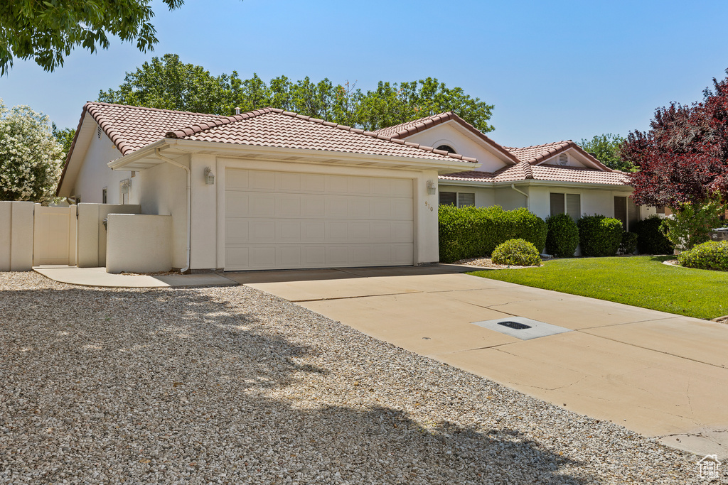Mediterranean / spanish home featuring an attached garage, stucco siding, a tiled roof, and concrete driveway