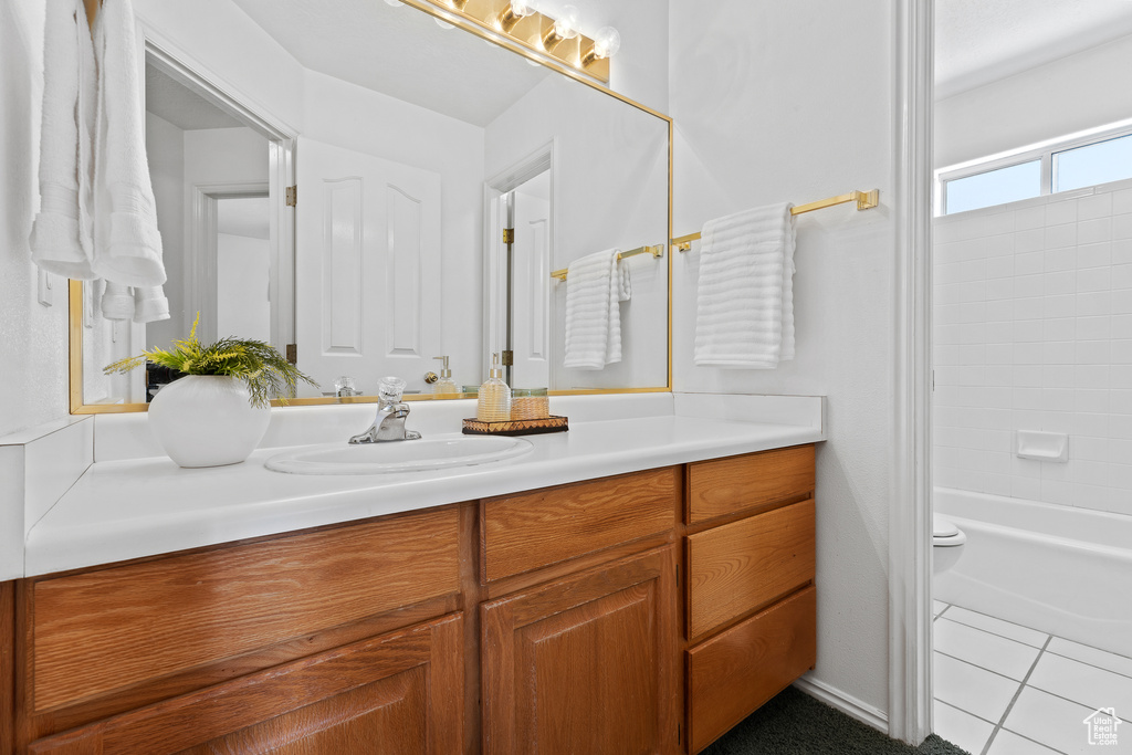 Bathroom featuring vanity, shower / bath combination, toilet, and tile patterned flooring