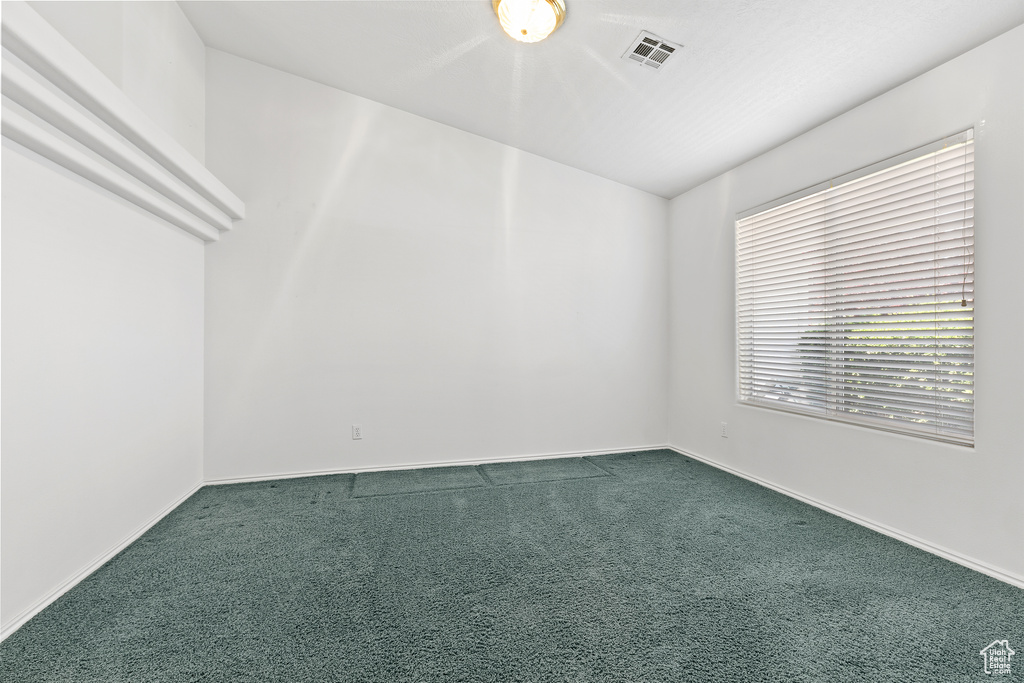 Spare room with dark colored carpet and baseboards