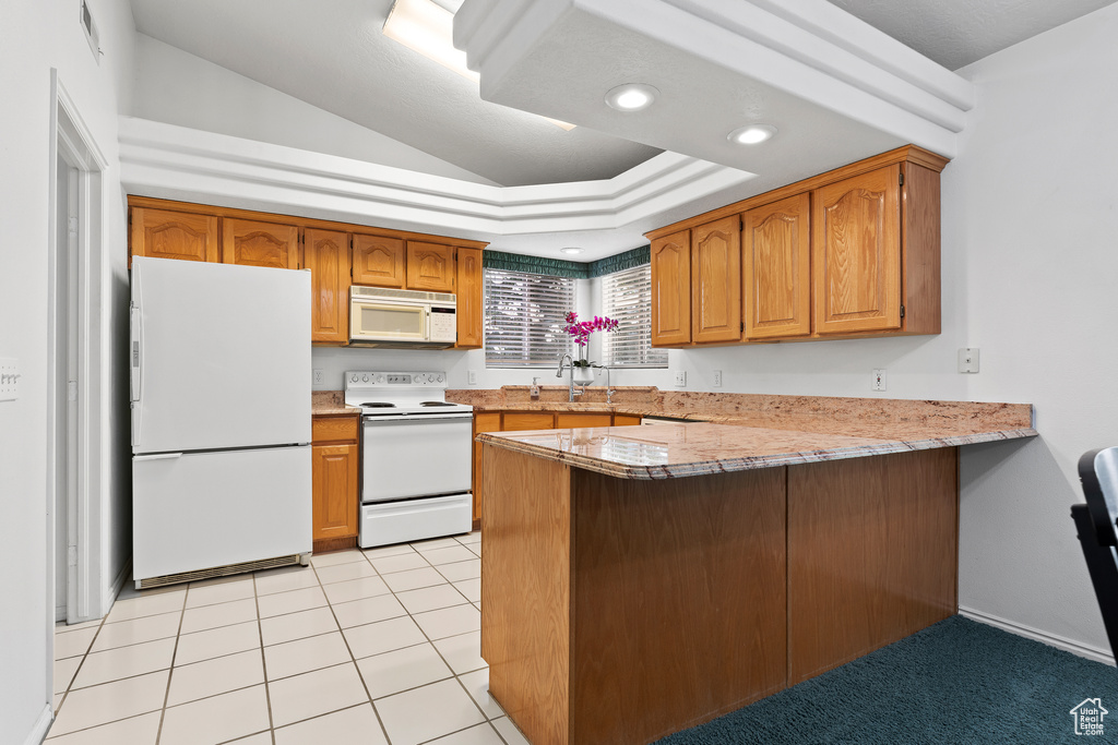 Kitchen with white appliances, a peninsula, lofted ceiling, brown cabinetry, and a sink