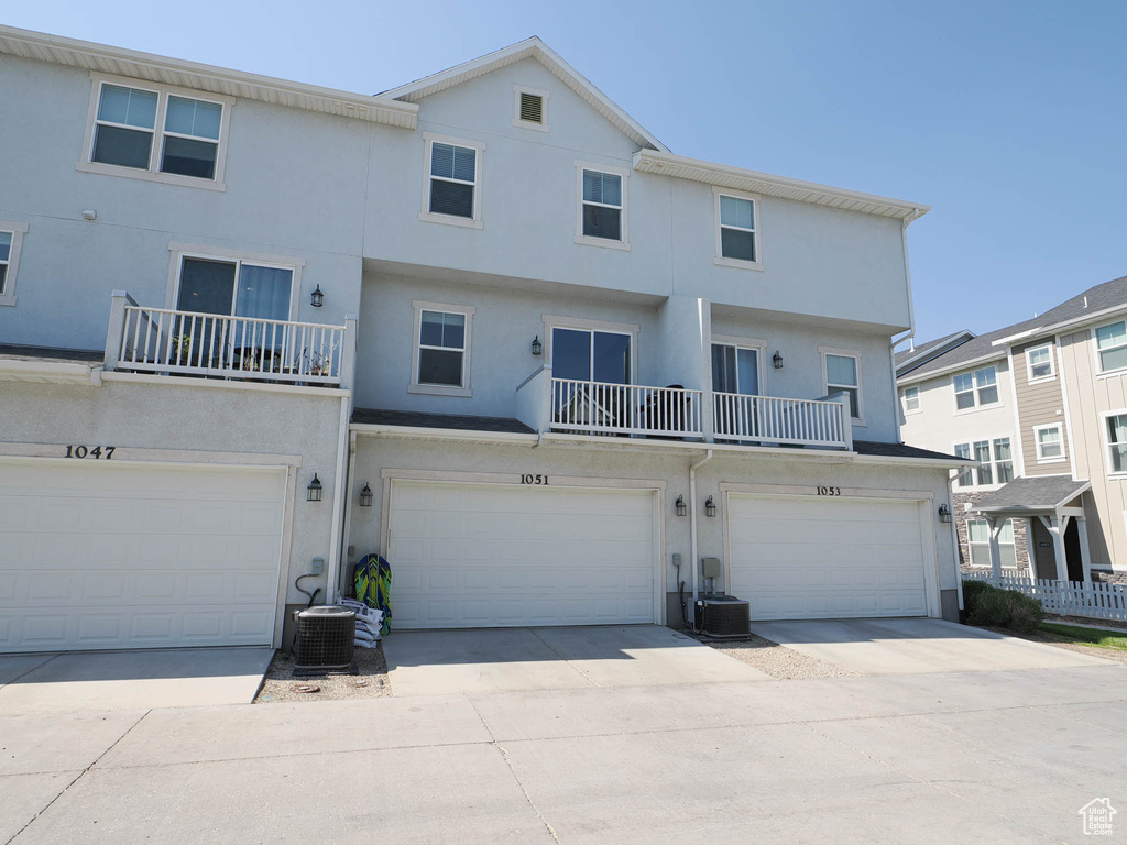 Rear view of property with stucco siding, a garage, and driveway