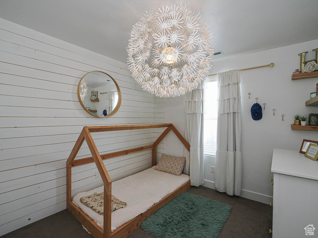 Bedroom with wood walls, carpet flooring, and a chandelier