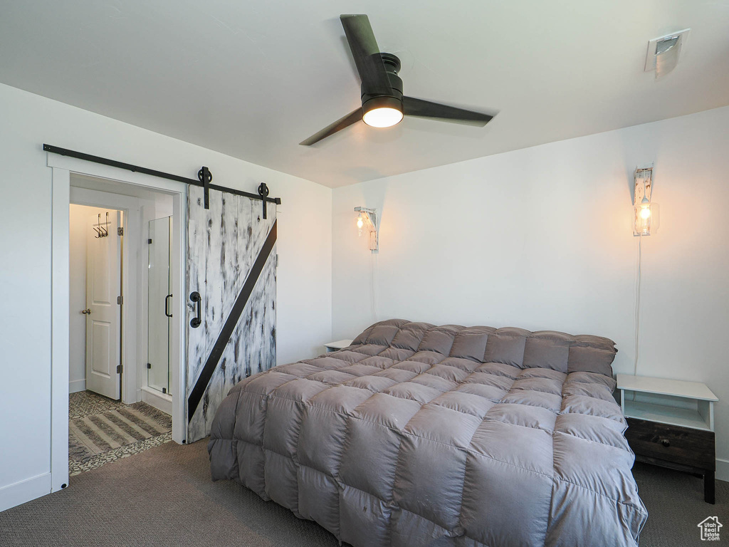 Bedroom with a barn door, carpet floors, and a ceiling fan