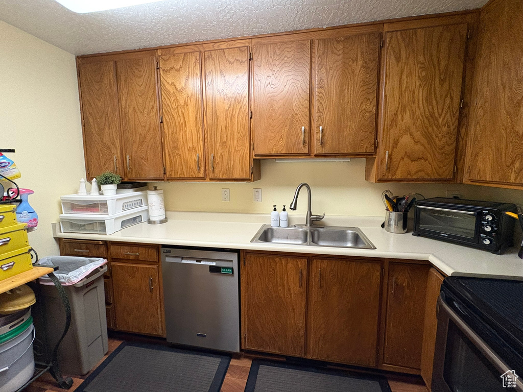 Kitchen with dishwasher, light countertops, brown cabinets, and range