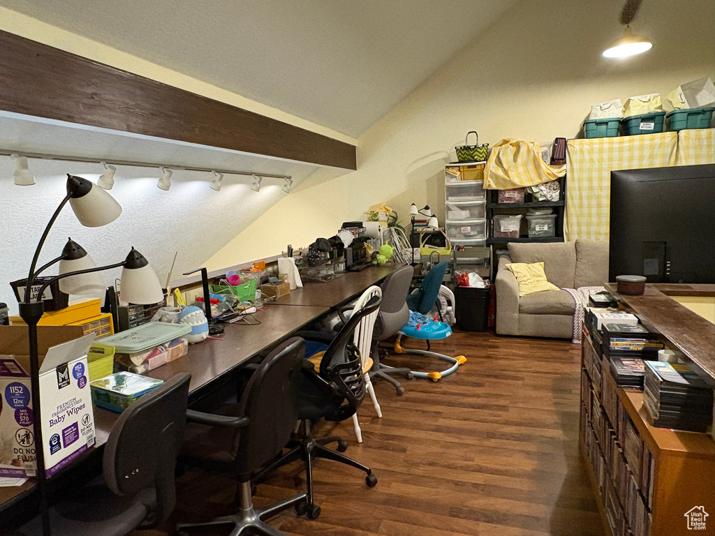 Office space with wood finished floors, track lighting, and vaulted ceiling