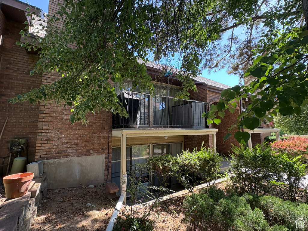 Back of property featuring brick siding and a balcony